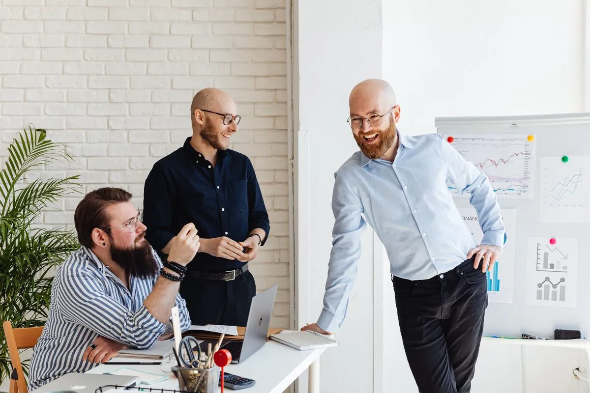 Drie collega's bespreken een strategie bij een whiteboard met cijfers