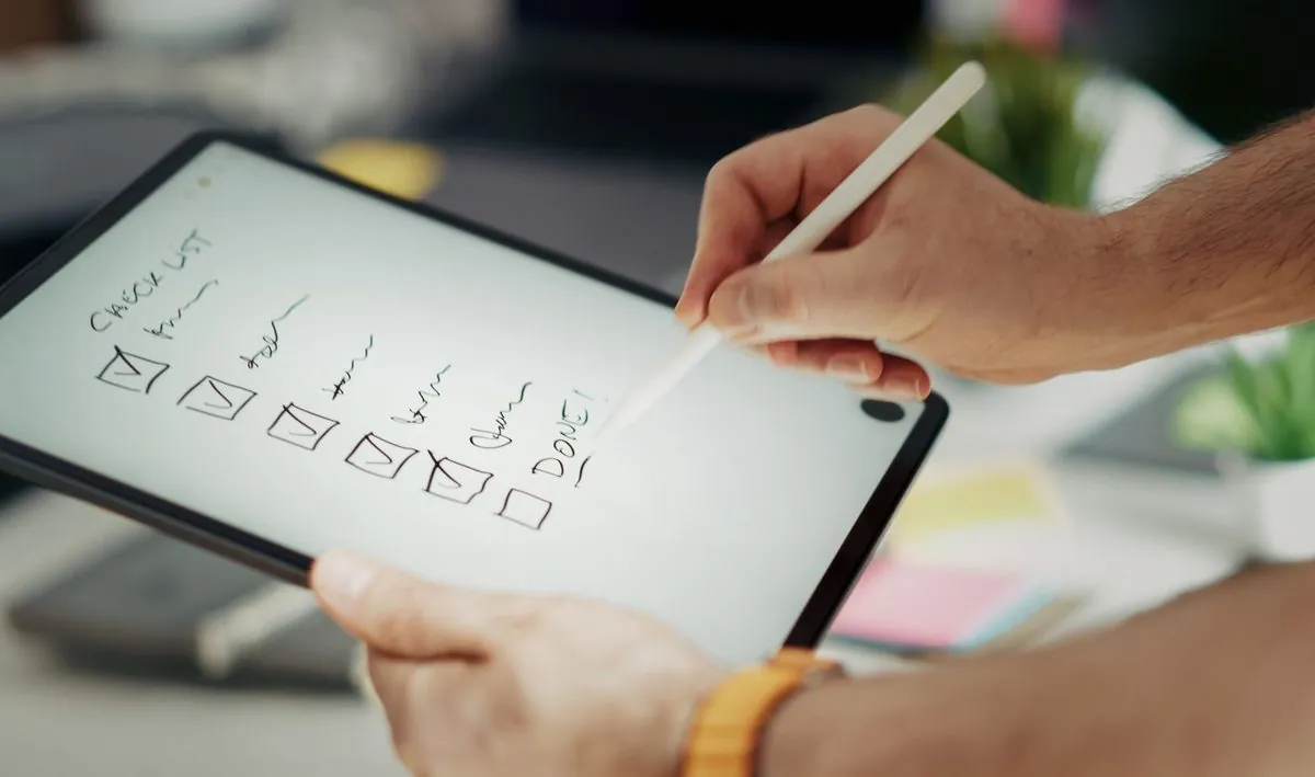 Close-up van een hand die een digitale checklist invult op een tablet