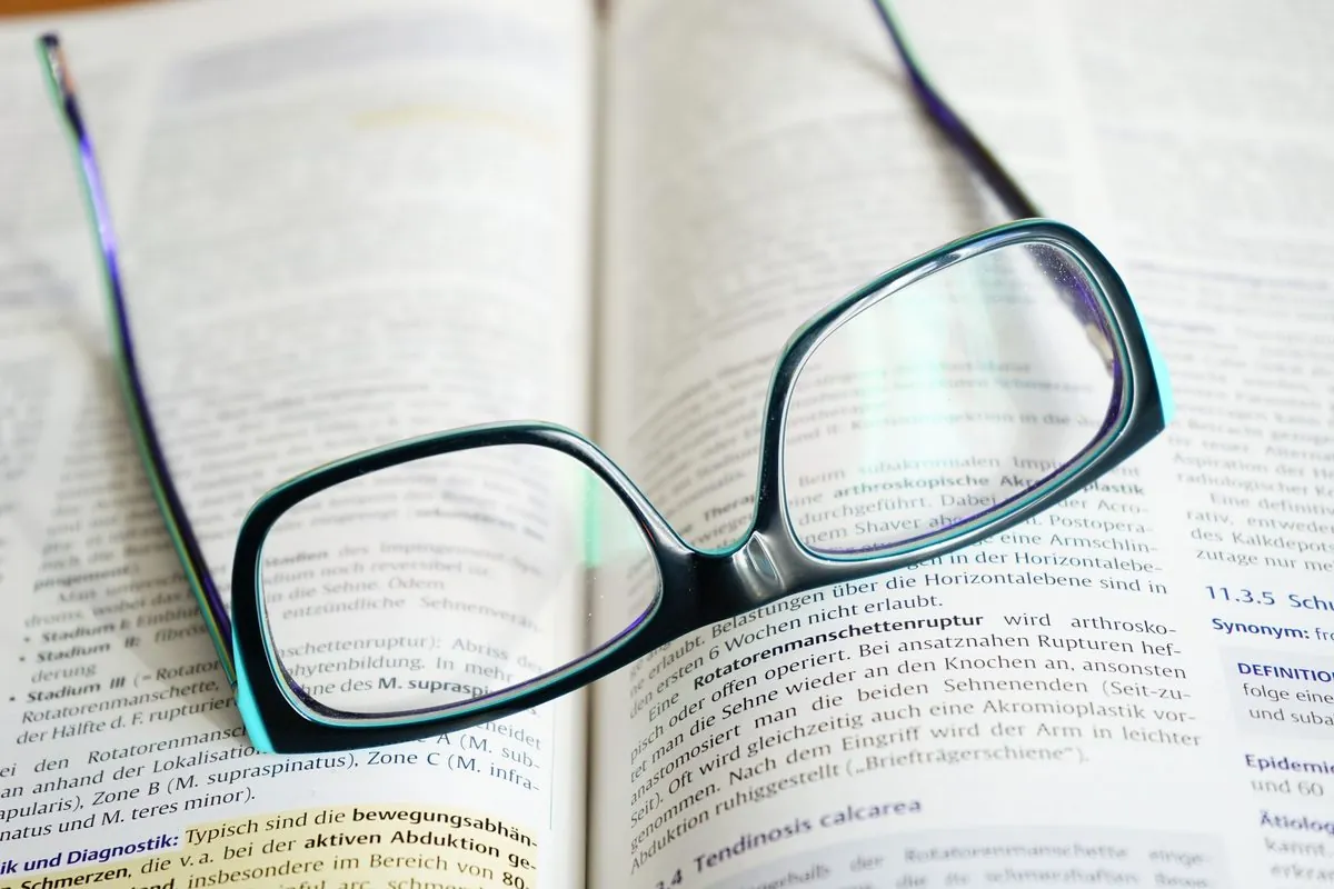 Een leesbril rust op een opengeslagen studieboek