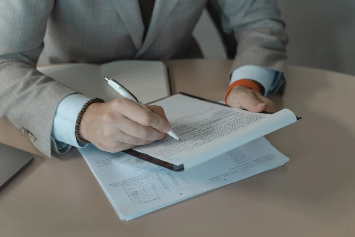 Close-up van iemand in pak die een document afvinkt op een klembord