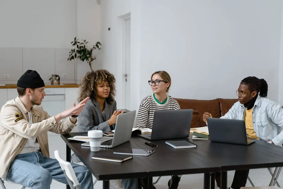 Een diverse groep collega's werkt samen aan een tafel met laptops