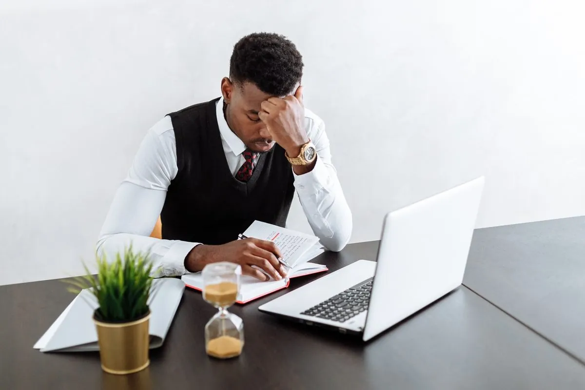 Een man werkt geconcentreerd op zijn laptop, met een zandloper ernaast