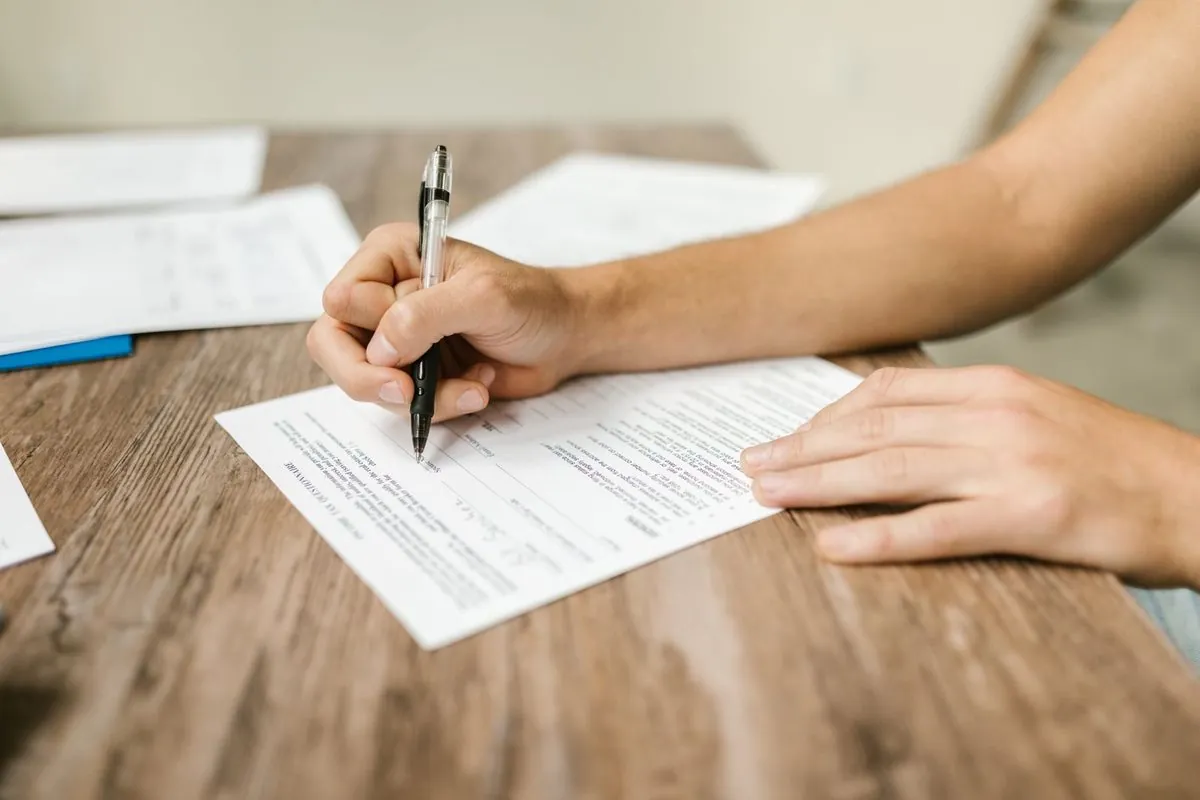 Close-up van een hand die met een pen een formulier invult